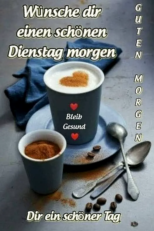 Einladendes Morgenarrangement mit zwei Kaffeetassen auf grauem Untergrund. Eine Tasse zeigt ein Herz aus Milchschaum, die andere enthält Kakaopulver. Kaffeebohnen, Löffel und ein blauer Stoff runden die gemütliche Dienstagsstimmung ab.