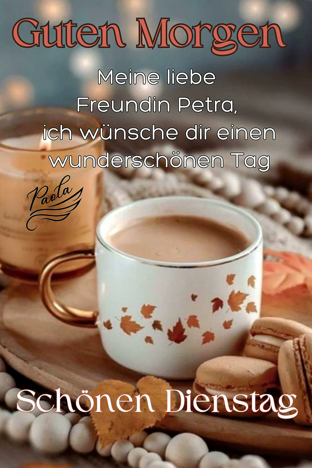 Nahaufnahme einer Kaffeetasse mit Herbstblättern, dazu eine brennende Kerze und Macarons auf einem Holzbrett. Weiße Perlen schmücken den Rand. Warme, ruhige Stimmung für einen schönen Dienstag.