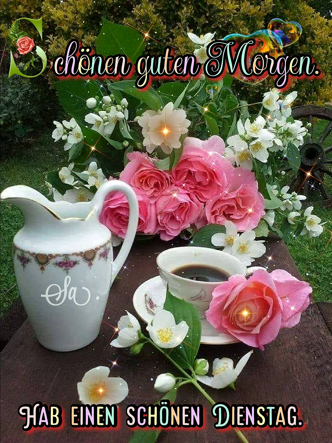 Ein Blumengarten mit einer Tasse Kaffee und einer Kanne auf einem Holztisch. Im Hintergrund sind Büsche und ein altes Wagenrad zu sehen. Der Tisch ist dekoriert mit rosa Rosen und weißen Blüten.
