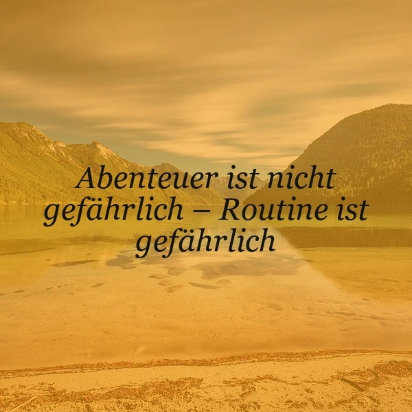 Ein stimmungsvolles Bild mit warmen Goldtönen zeigt eine ruhige Berglandschaft mit einem See im Sonnenuntergang. Darauf steht das motivierende Zitat: 'Abenteuer ist nicht gefährlich – Routine ist gefährlich', das zum Nachdenken anregt und Mut macht.
