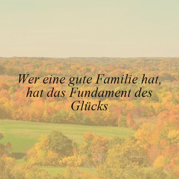 Ein Foto einer idyllischen Landschaft mit einer grünen Wiese und farbenfrohen Herbstbäumen. Im Vordergrund ist ein Zitat in schwarzer Schrift zu sehen: 'Wer eine gute Familie hat, hat das Fundament des Glücks'. Die Stimmung ist friedlich und herbstlich.